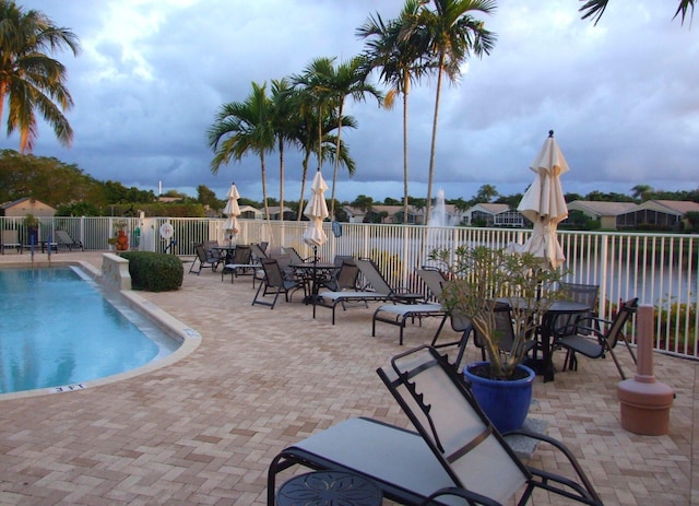 community pool with outdoor dining space, a patio area, and fence