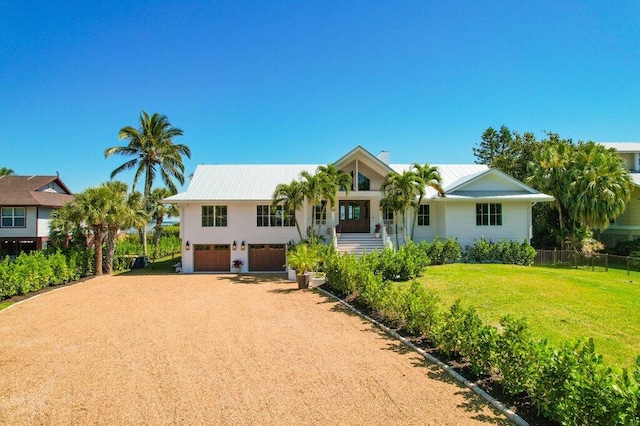 view of front of house featuring metal roof, a front lawn, driveway, and fence