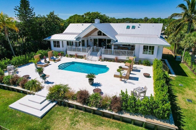 rear view of house featuring a wooden deck, a yard, a patio area, and metal roof