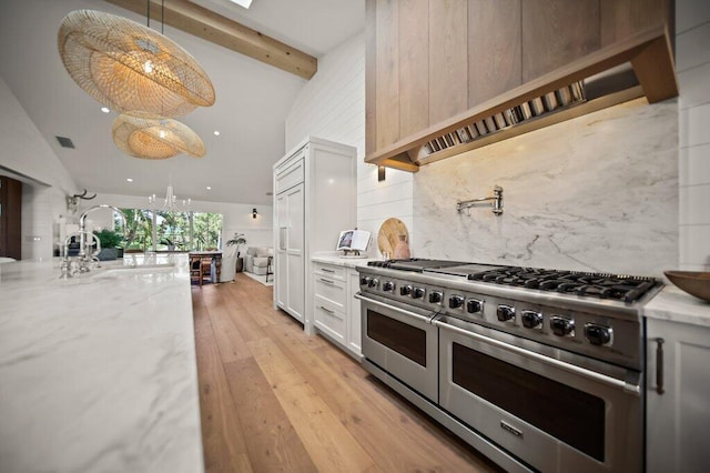 kitchen with double oven range, light stone countertops, beam ceiling, decorative backsplash, and light wood-style floors