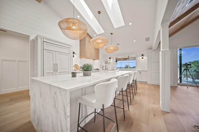 kitchen with visible vents, a spacious island, a skylight, a decorative wall, and light wood-type flooring