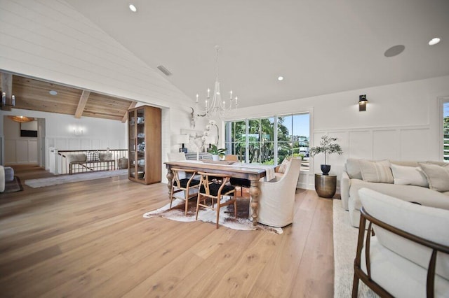 dining room featuring beamed ceiling, hardwood / wood-style flooring, an inviting chandelier, wainscoting, and a decorative wall