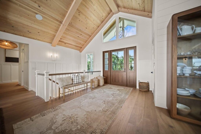 foyer entrance with beamed ceiling, high vaulted ceiling, hardwood / wood-style floors, wooden ceiling, and wainscoting