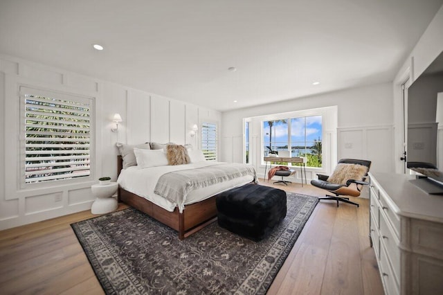 bedroom with recessed lighting, light wood-style floors, and a decorative wall