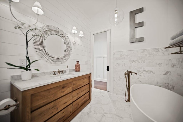 bathroom featuring a wainscoted wall, marble finish floor, vanity, and a freestanding tub