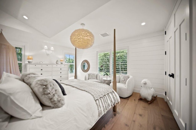 bedroom featuring vaulted ceiling, wooden walls, recessed lighting, and wood-type flooring