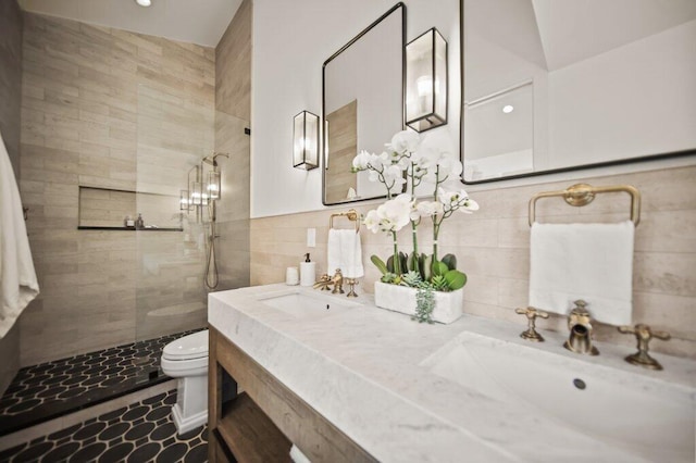 full bath featuring toilet, a walk in shower, tile walls, and a sink