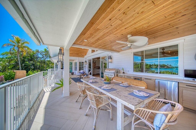 deck featuring outdoor dining area, area for grilling, ceiling fan, and exterior kitchen