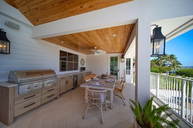 view of patio with grilling area, wine cooler, outdoor dining area, area for grilling, and a ceiling fan