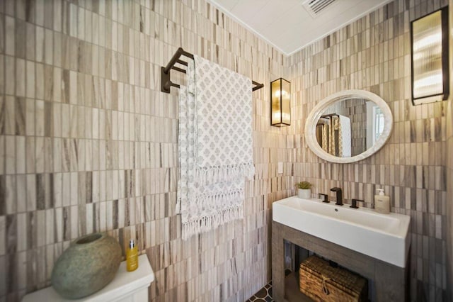 bathroom with tile walls, visible vents, and a sink