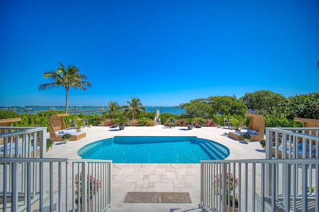 outdoor pool with a patio area and a water view