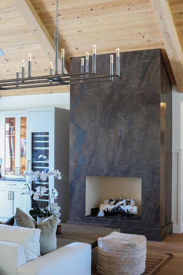 living room featuring wood finished floors, beamed ceiling, wood ceiling, and a fireplace with raised hearth