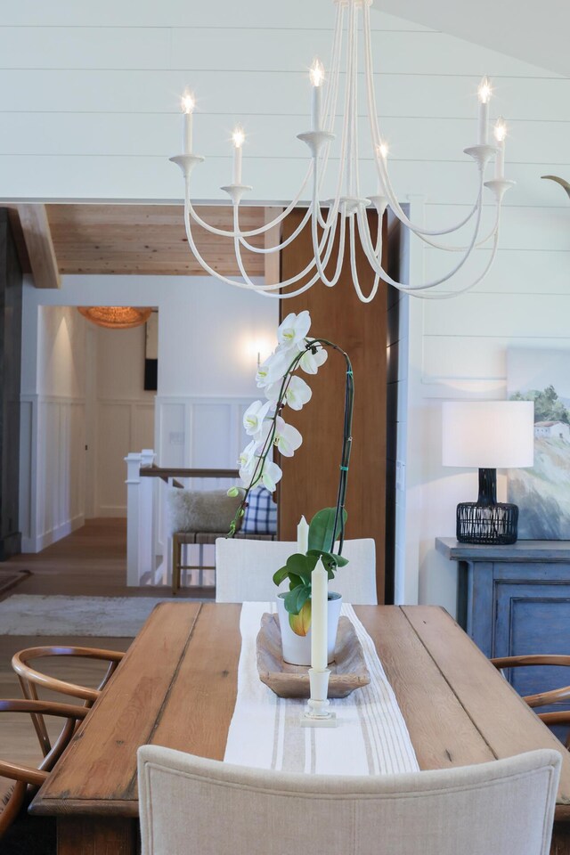 interior space with a notable chandelier, a wainscoted wall, a decorative wall, and vaulted ceiling