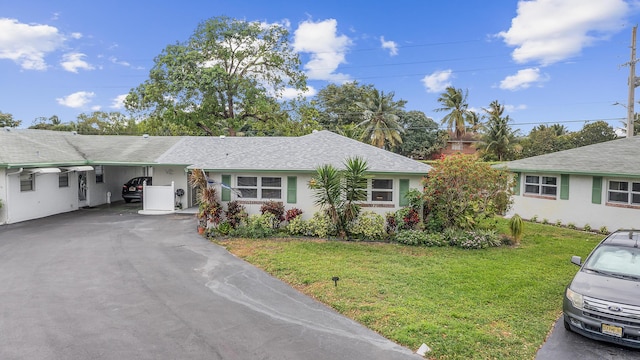 ranch-style home featuring stucco siding, a front lawn, driveway, a shingled roof, and an attached carport