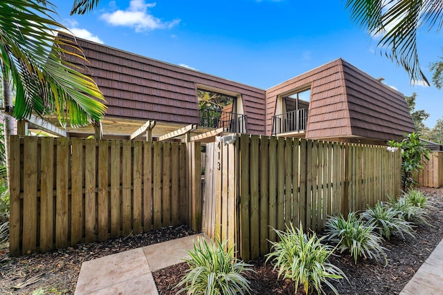 view of side of property with mansard roof and fence