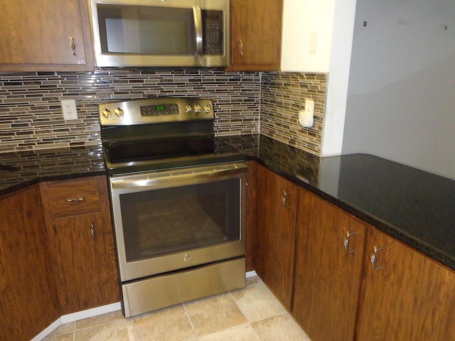 kitchen featuring backsplash, appliances with stainless steel finishes, light tile patterned flooring, and brown cabinetry