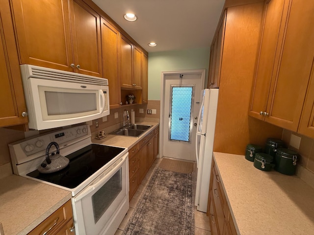 kitchen featuring a sink, white appliances, tasteful backsplash, and brown cabinetry