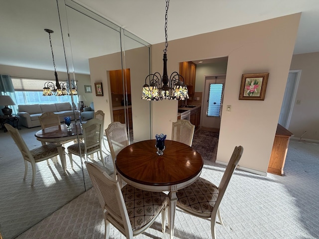 dining space with an inviting chandelier, light colored carpet, and baseboards