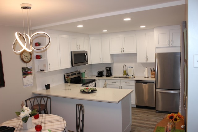 kitchen with appliances with stainless steel finishes, light countertops, a peninsula, and a sink