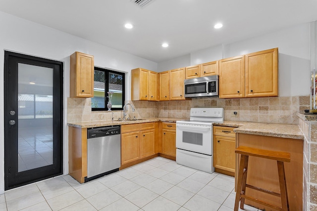 kitchen featuring a sink, recessed lighting, appliances with stainless steel finishes, light tile patterned flooring, and decorative backsplash