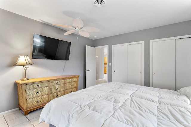 bedroom featuring visible vents, multiple closets, a ceiling fan, light tile patterned floors, and baseboards