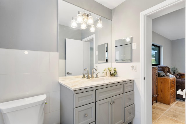 bathroom featuring toilet, tile walls, ensuite bath, and vanity