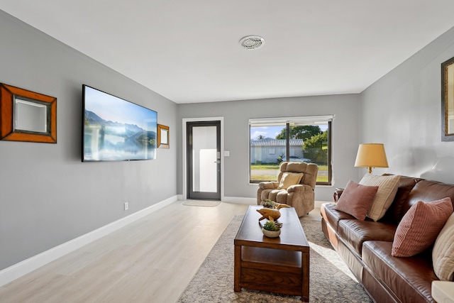 living room featuring visible vents, baseboards, and light wood finished floors