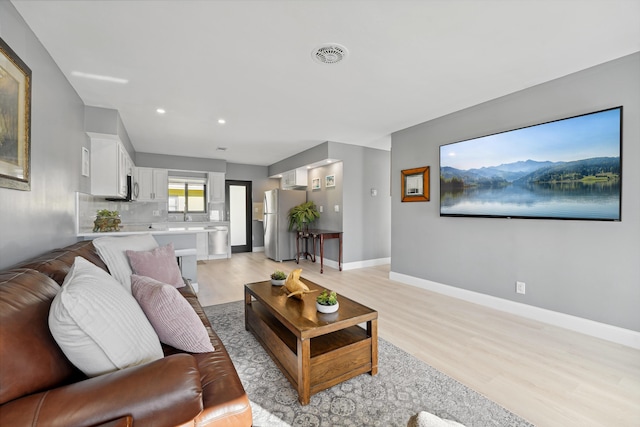 living area featuring light wood-type flooring, visible vents, baseboards, and recessed lighting