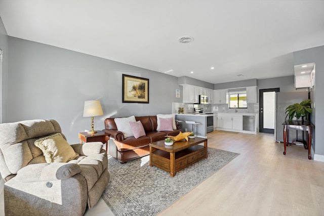 living area with visible vents, recessed lighting, and light wood-style floors