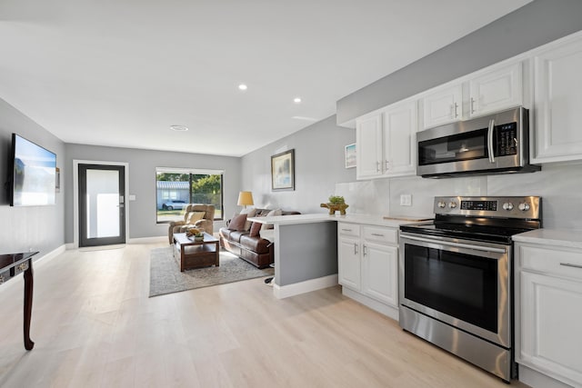 kitchen with light wood finished floors, open floor plan, light countertops, appliances with stainless steel finishes, and white cabinets