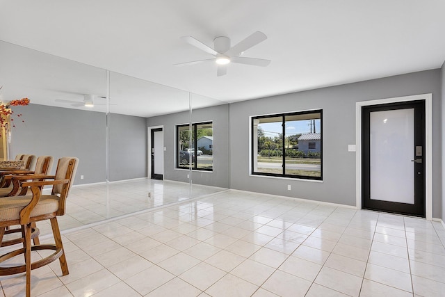 spare room with light tile patterned floors, a ceiling fan, and baseboards