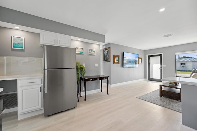 kitchen with baseboards, freestanding refrigerator, light countertops, white cabinetry, and light wood-type flooring