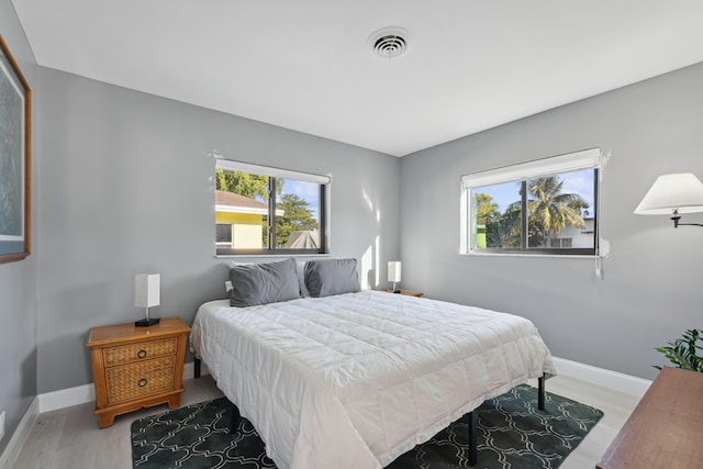 bedroom with visible vents, baseboards, and wood finished floors