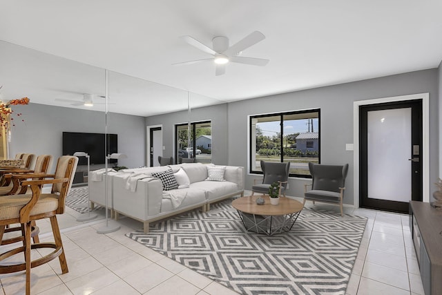 living area featuring light tile patterned floors, baseboards, and ceiling fan