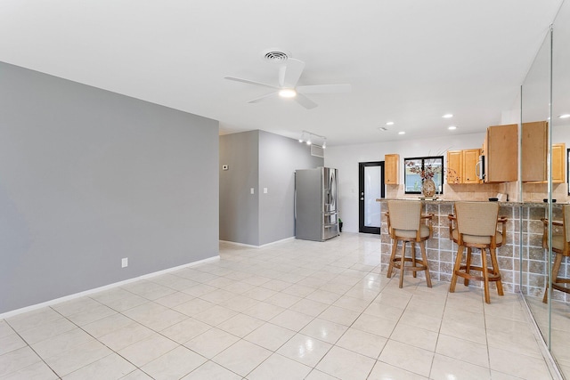 kitchen featuring visible vents, baseboards, a peninsula, decorative backsplash, and stainless steel refrigerator with ice dispenser