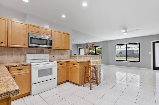 kitchen featuring a peninsula, electric stove, stainless steel microwave, tasteful backsplash, and open floor plan