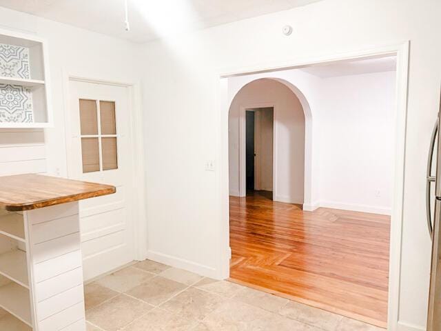 hallway with baseboards and arched walkways