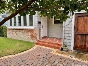 entrance to property with brick siding and fence