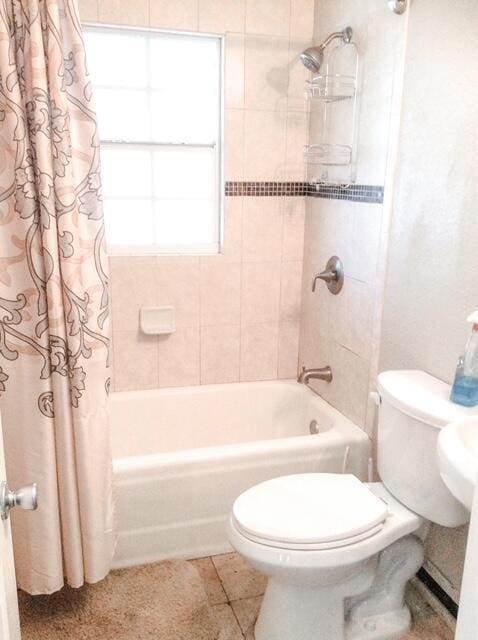 bathroom with tile patterned flooring, toilet, and shower / tub combo with curtain