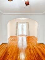 spare room featuring arched walkways and wood finished floors