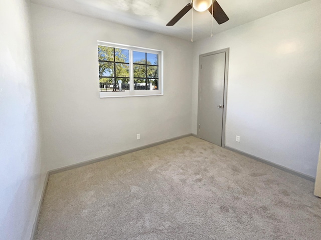 carpeted empty room featuring ceiling fan and baseboards