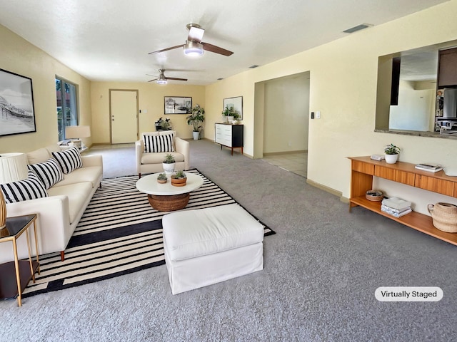 living area featuring visible vents, carpet flooring, baseboards, and ceiling fan