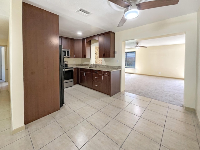 kitchen featuring visible vents, light colored carpet, appliances with stainless steel finishes, a ceiling fan, and a sink