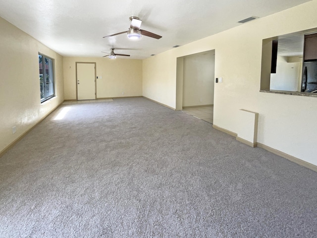 carpeted spare room featuring baseboards, visible vents, and ceiling fan