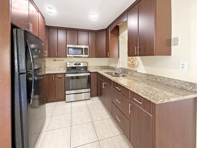 kitchen featuring light tile patterned floors, stainless steel appliances, and a sink