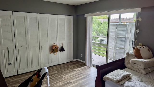 bedroom with light wood-style flooring, baseboards, and access to exterior