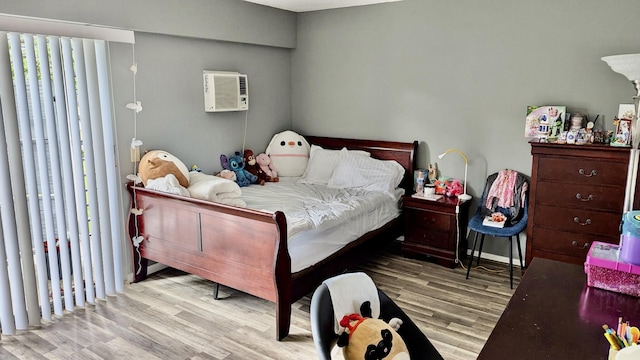 bedroom with a wall unit AC and wood finished floors