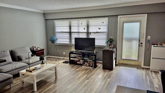 living area with ornamental molding, wood finished floors, baseboards, and a textured ceiling