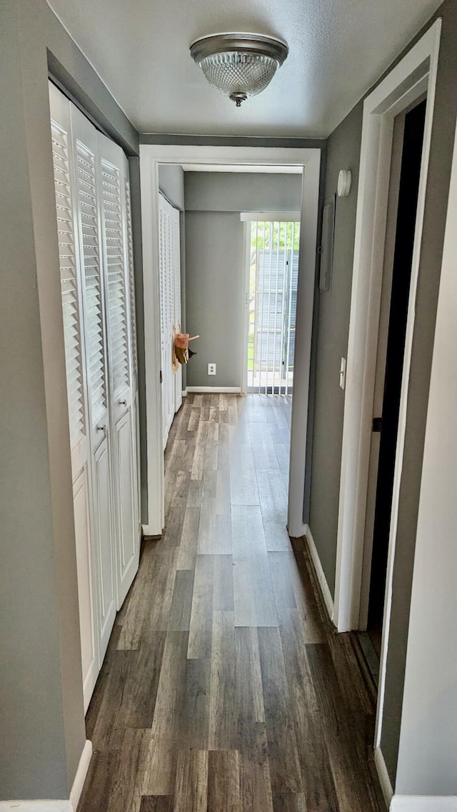 corridor featuring dark wood-type flooring and baseboards