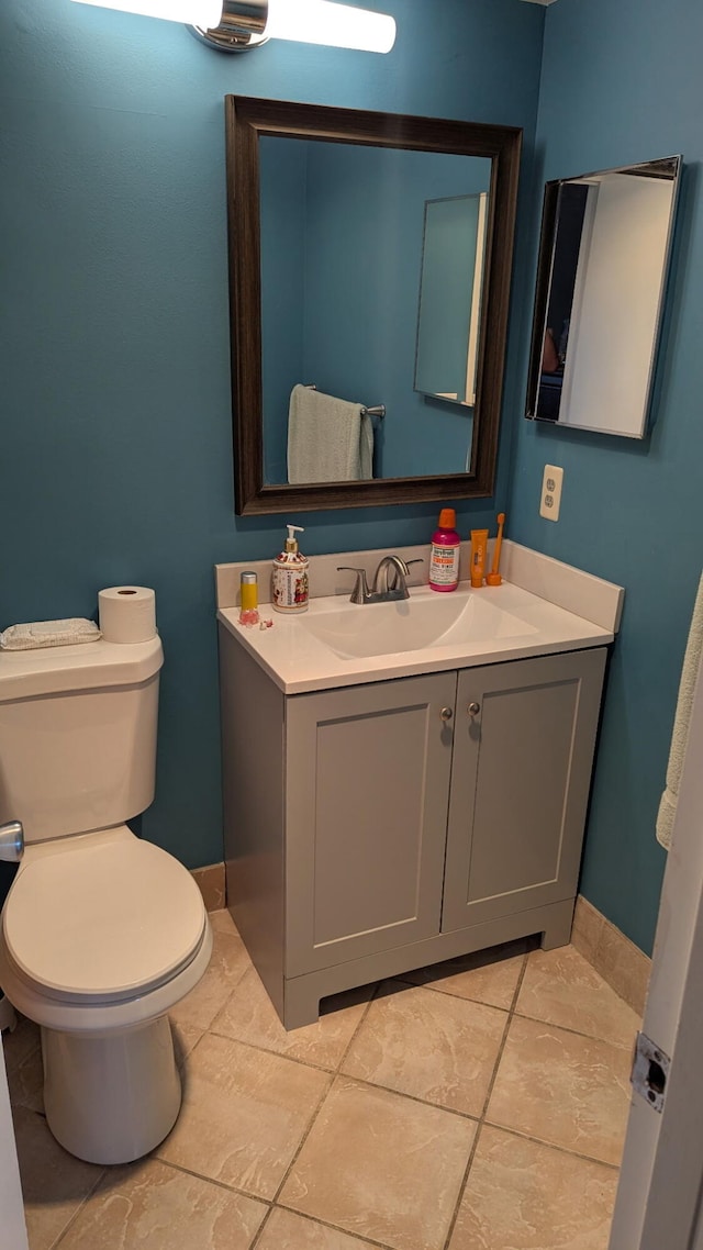 half bathroom with baseboards, toilet, and vanity